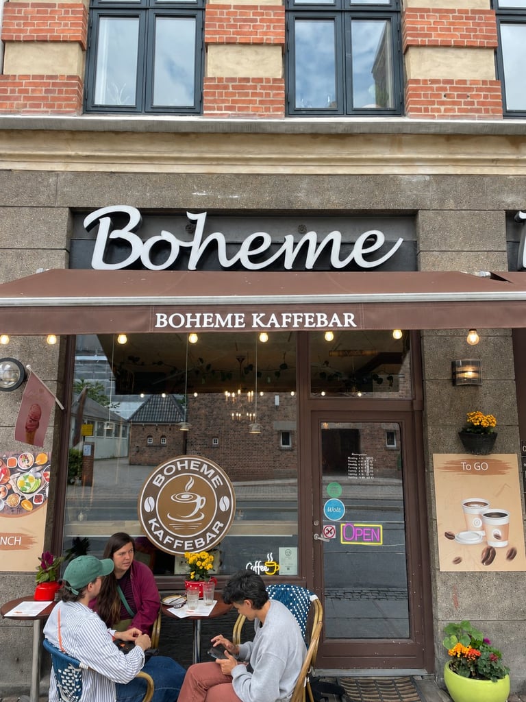 Boheme Kaffebar storefront with customers seated at outdoor tables beneath a brick and stone building facade