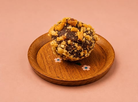 Chocolate chip cookie on a wooden round plate against a pink background